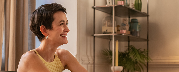Woman looking to the side smiling while sitting on a couch