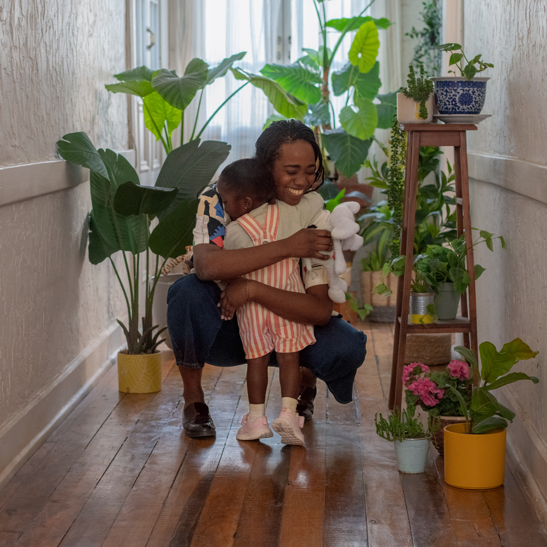Mother and son hugging in a hallway with plants