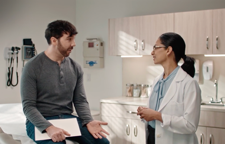 Brown haired man speaking to a doctor in an office