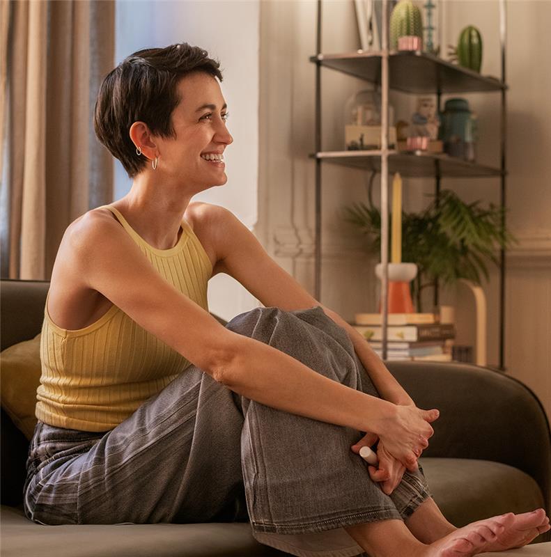 Woman looking to the side smiling while sitting on a couch